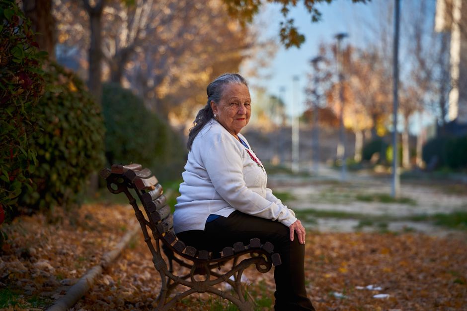 Mujer mayor sentada en un banco del parque en otoño, disfrutando de un momento tranquilo en San Sebastián de los Reyes.