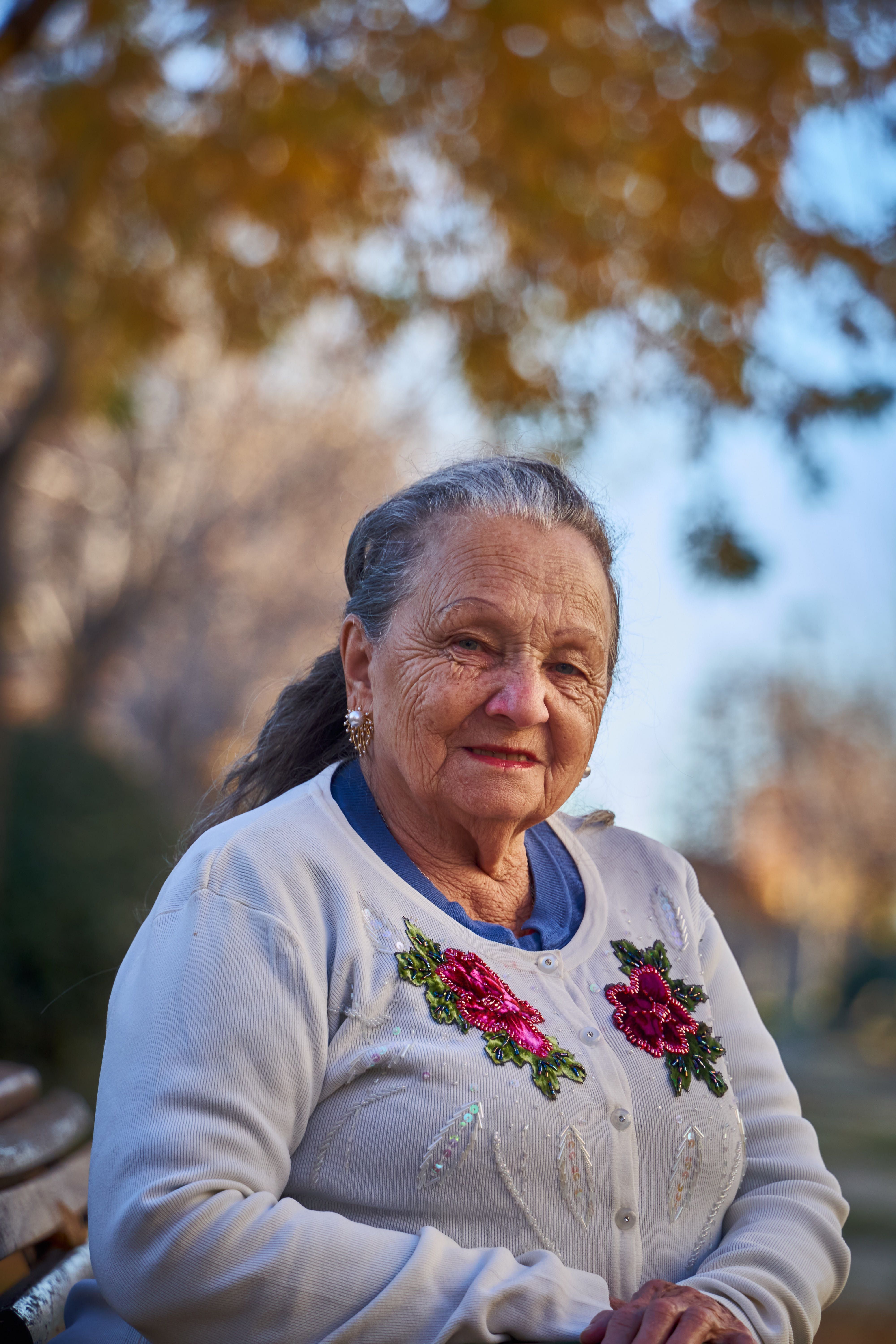 Fotomural Un retrato sereno de una anciana sonriente al aire libre en un día soleado.