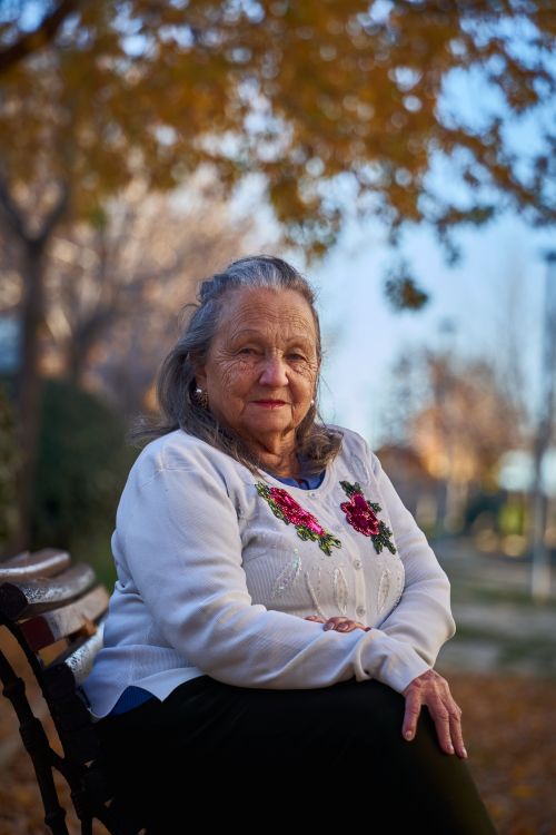 Free Portrait of an elderly woman sitting on a park bench in San Sebastián de los Reyes, Spain. Stock Photo
