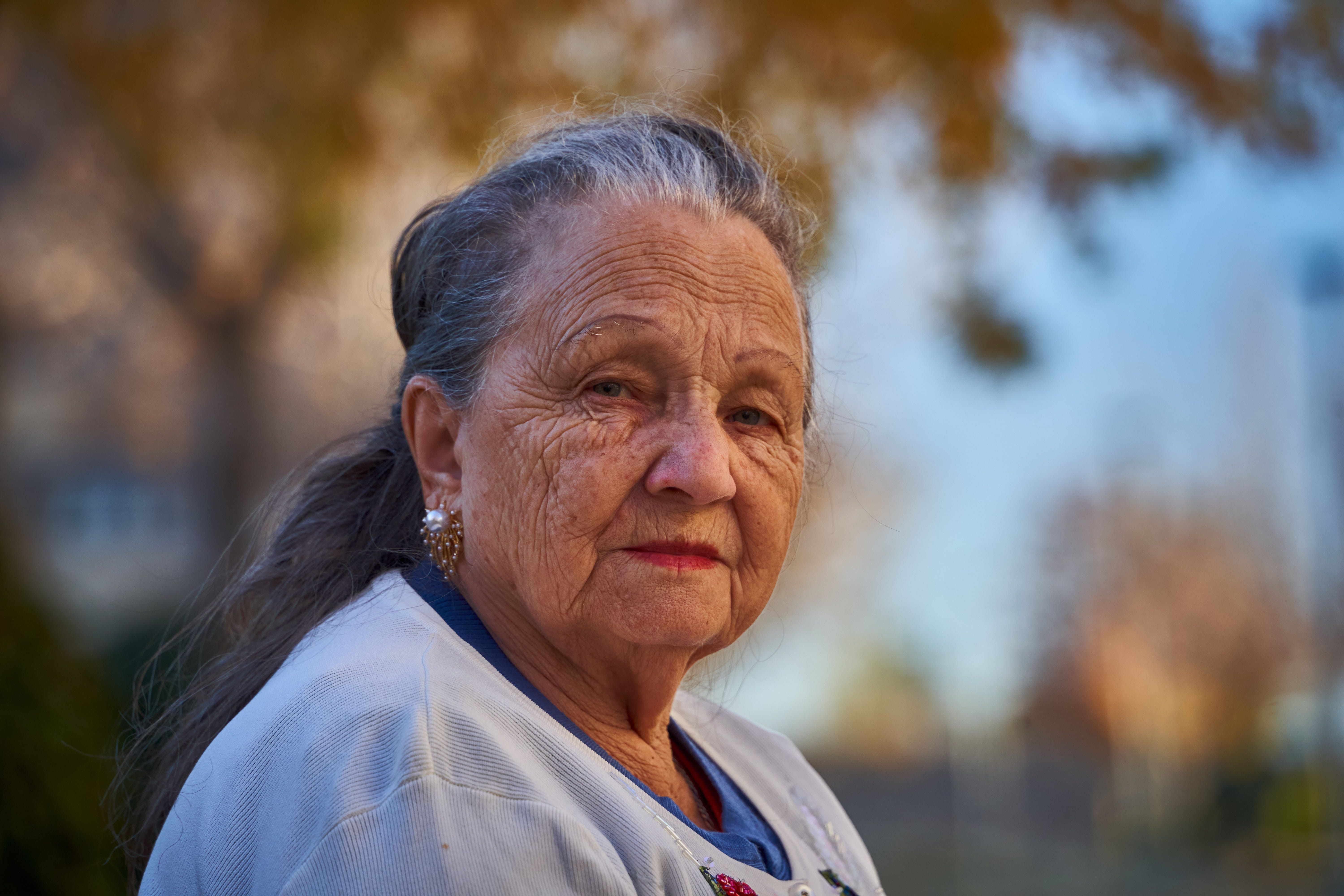 Senior woman with thoughtful expression in a sunny outdoor setting.