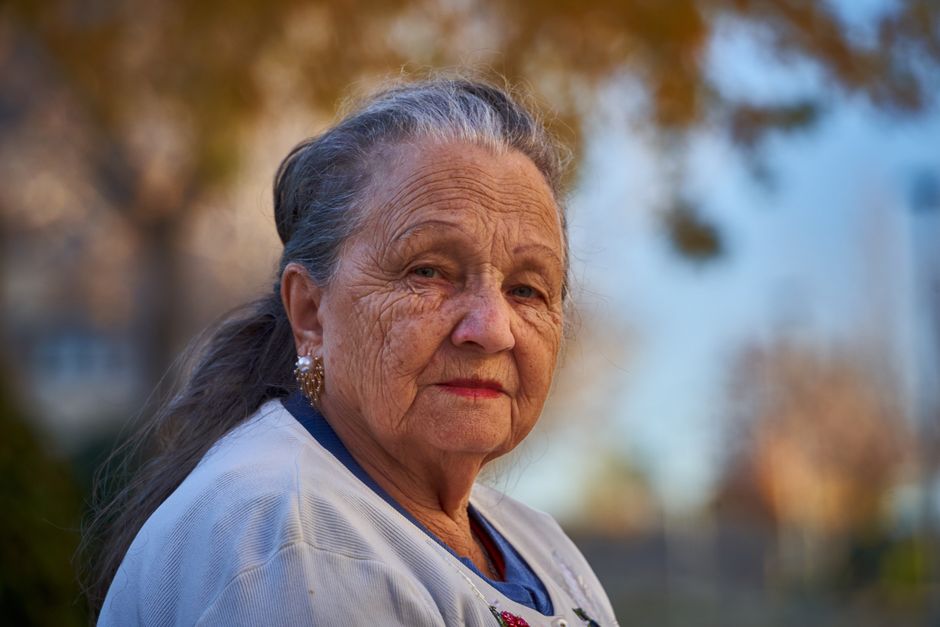 Senior woman with thoughtful expression in a sunny outdoor setting.