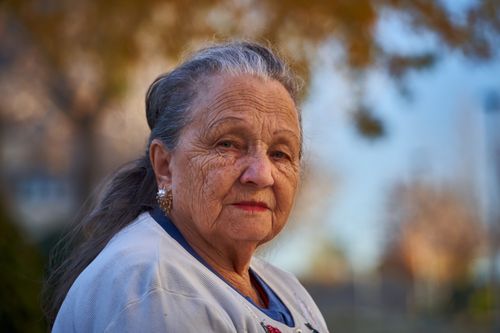 Free Senior woman with thoughtful expression in a sunny outdoor setting. Stock Photo