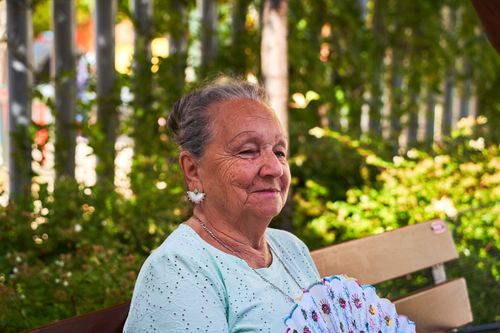 Free A senior woman enjoys a sunny day outdoors with a fan in San Sebastián de los Reyes, Spain. Stock Photo