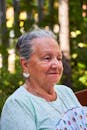 Elderly Woman with Fan in Outdoor Setting