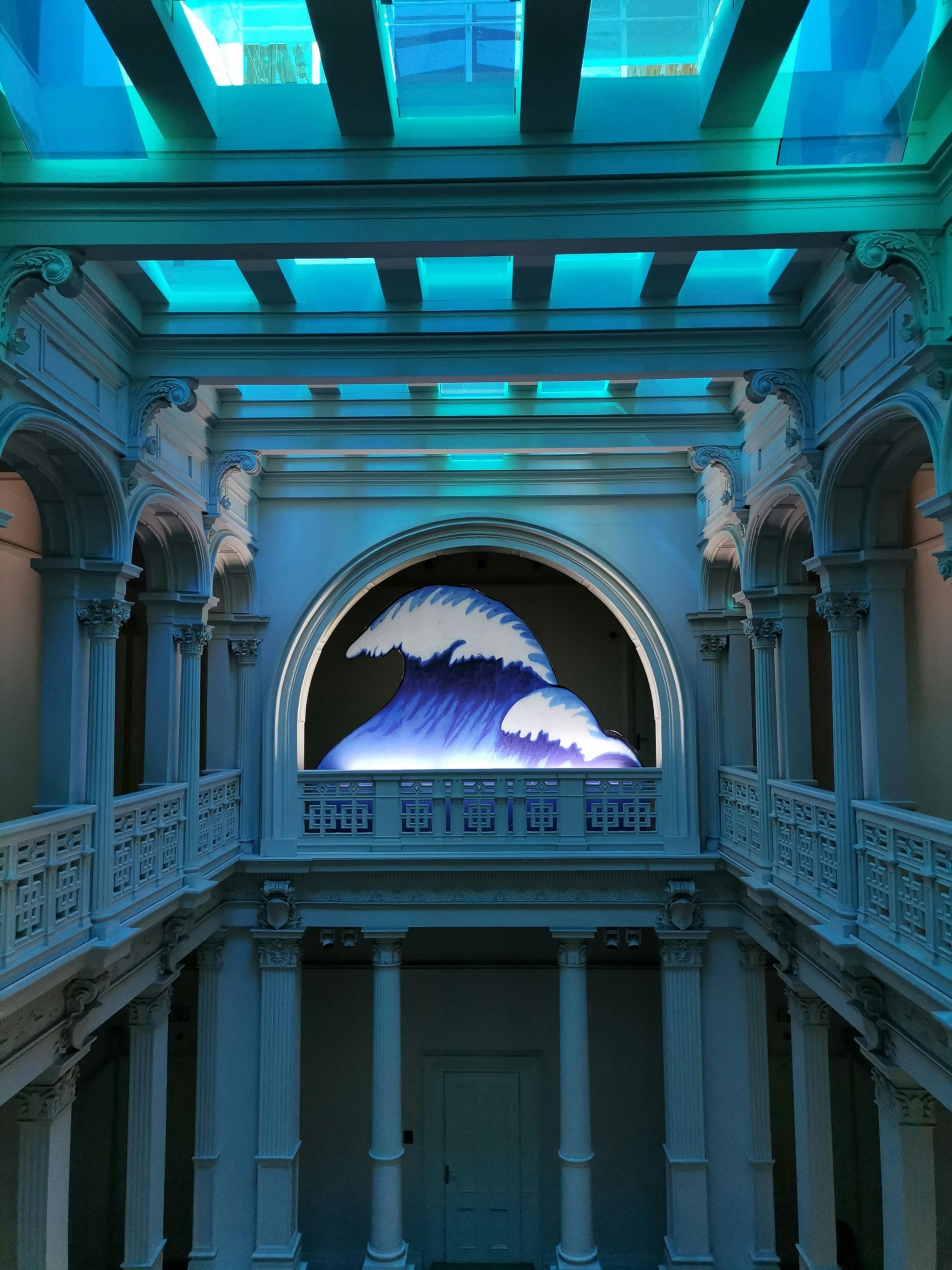 Futuristic architectural design with oceanic wave art installation under vibrant lighting.