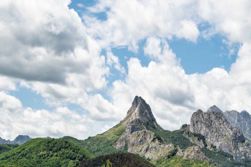 Free Stunning landscape of rugged mountain peaks and a bright blue sky with fluffy clouds. Stock Photo