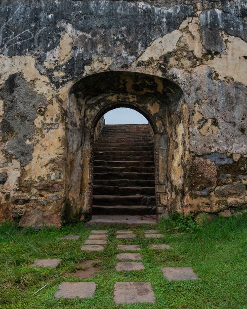 Free A weathered stone archway leading to stairs in an ancient fort with mossy walls. Stock Photo