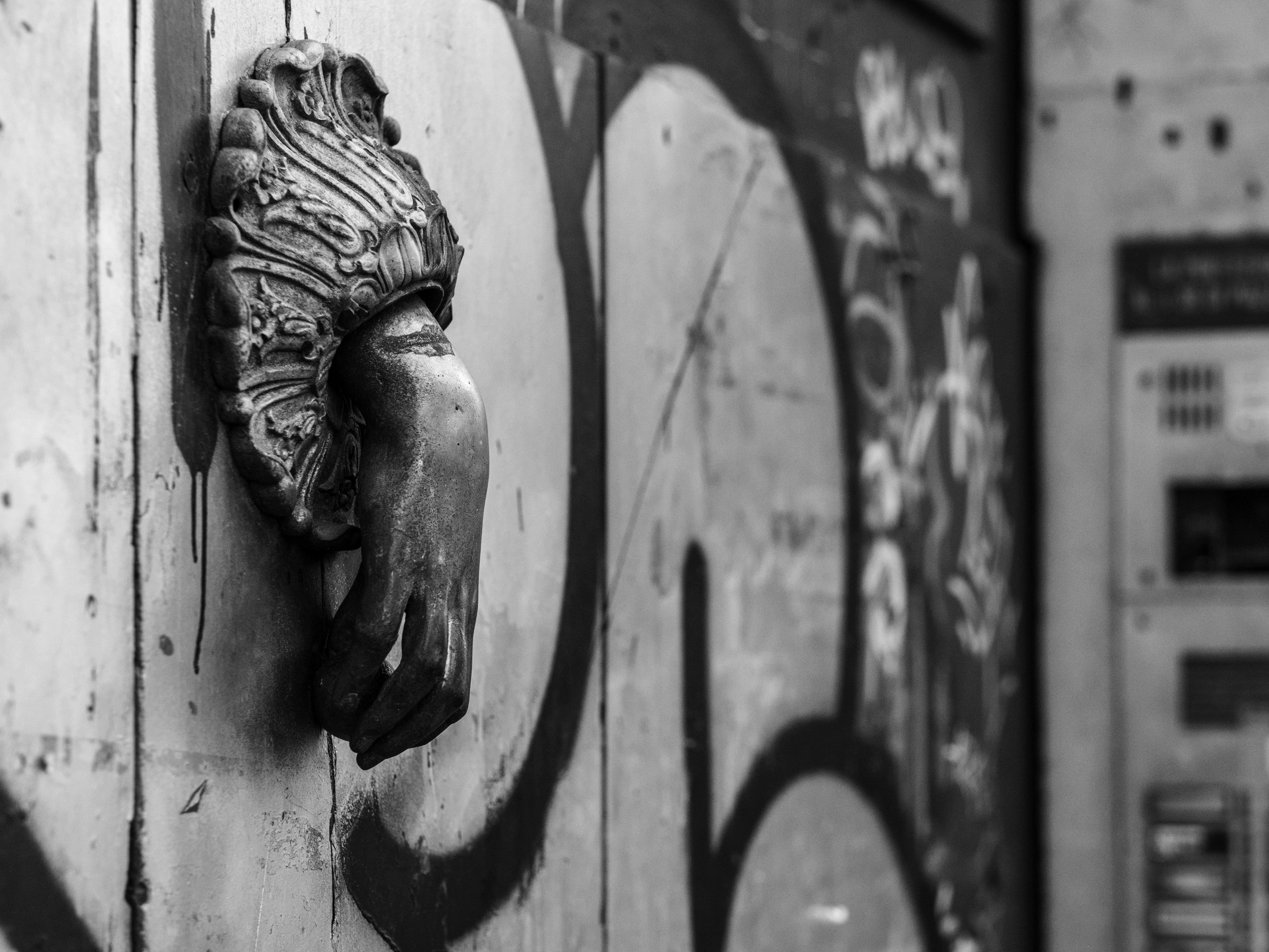 Gratuit Image en noir et blanc d'un heurtoir de porte ancien se détachant sur un mur couvert de graffitis à Catane, en Sicile. Photos