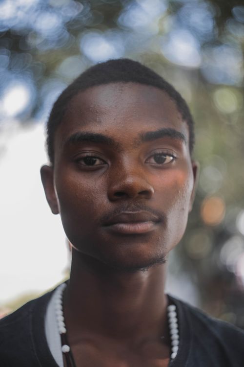 Free A young man gazes thoughtfully with a soft bokeh background, creating a warm portrait. Stock Photo