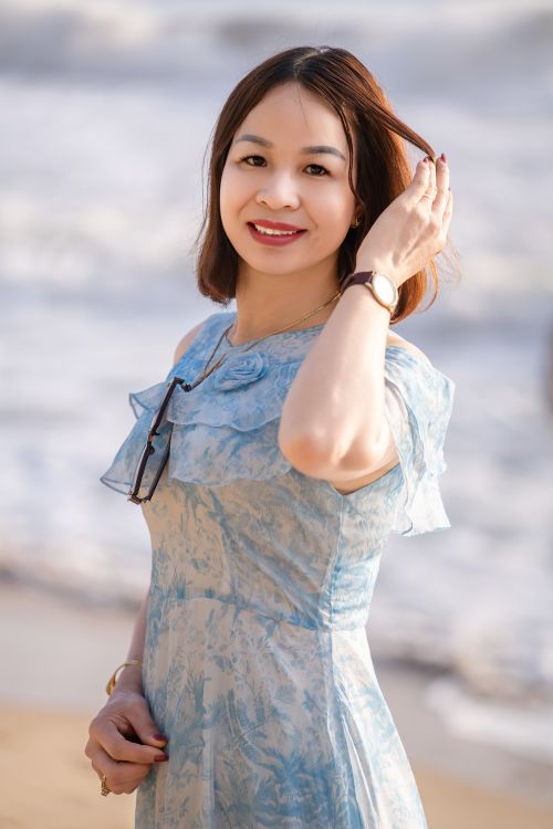 Free A cheerful woman stands on a sunny beach, enjoying the ocean breeze. Stock Photo