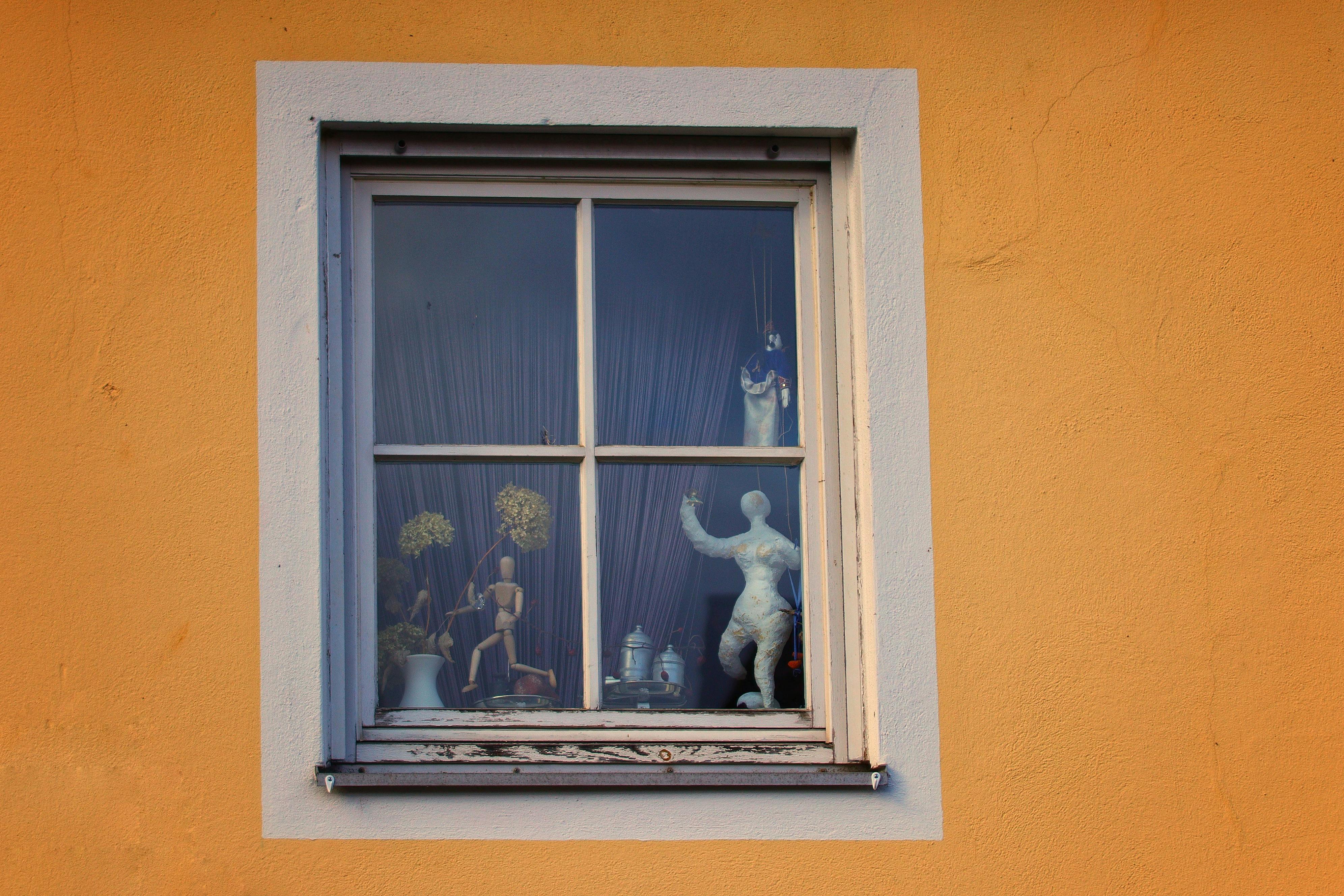 Gratis Kreativ utstilling av figurer og gjenstander i et vindu, livlig gul vegg. Arkivbilde