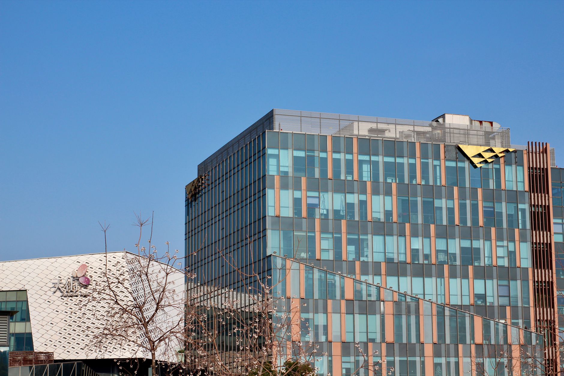 Two modern office buildings with glass facades under a clear blue sky.