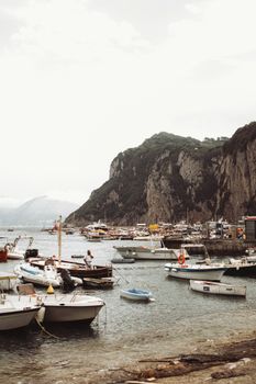 Charming marina in Capri, Italy with boats against a rocky backdrop.