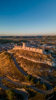 Drone shot capturing the historic Peñafiel Castle in Castilla y León during sunset.