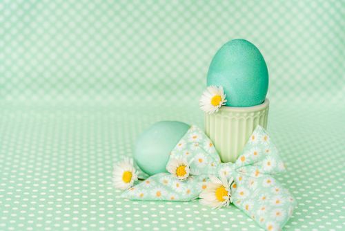 Free Charming pastel green Easter eggs decorated with daisies and a bow, set on a dotted green background. Stock Photo