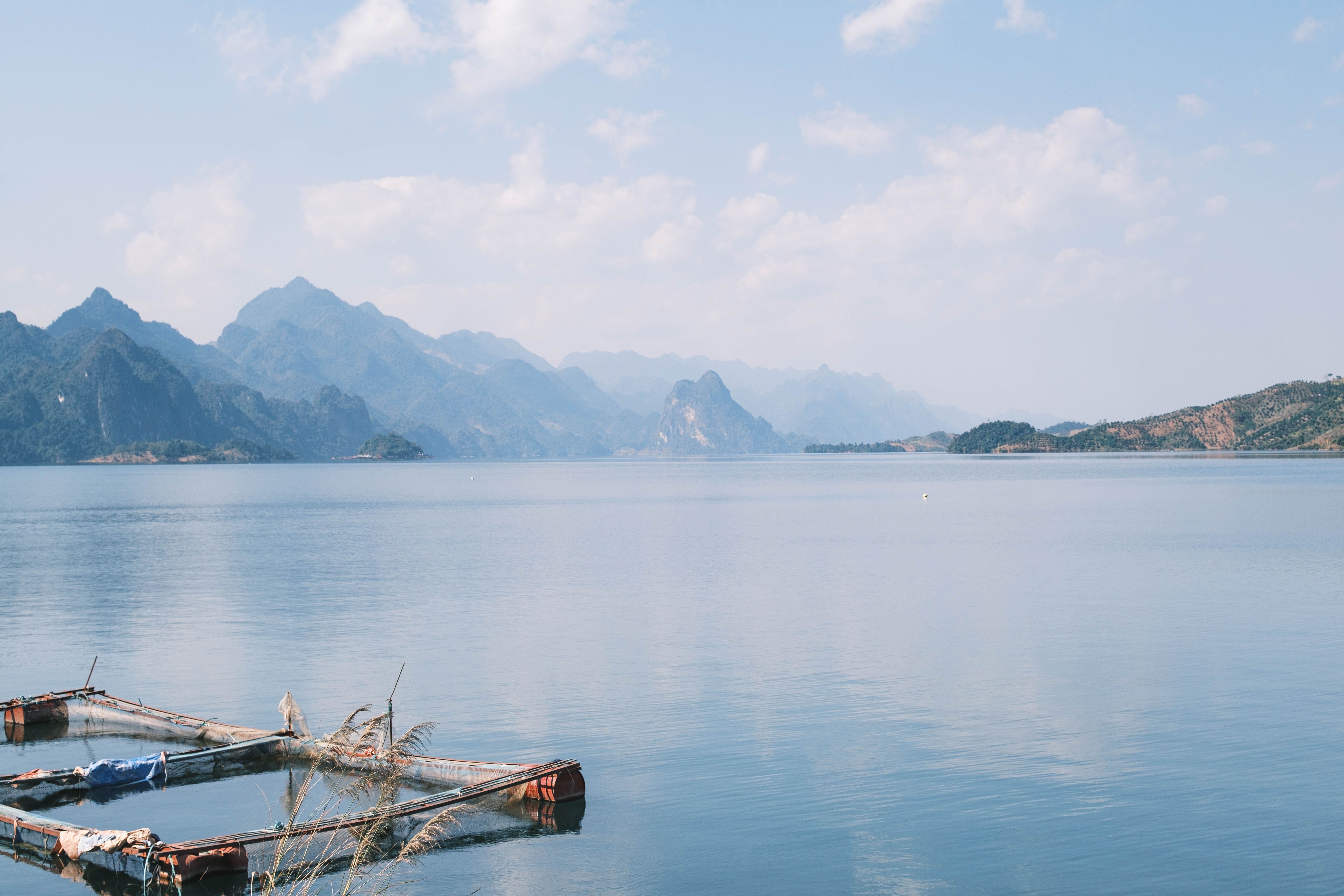 A serene mountain lake with clear blue sky and distant peaks reflecting in the calm water.