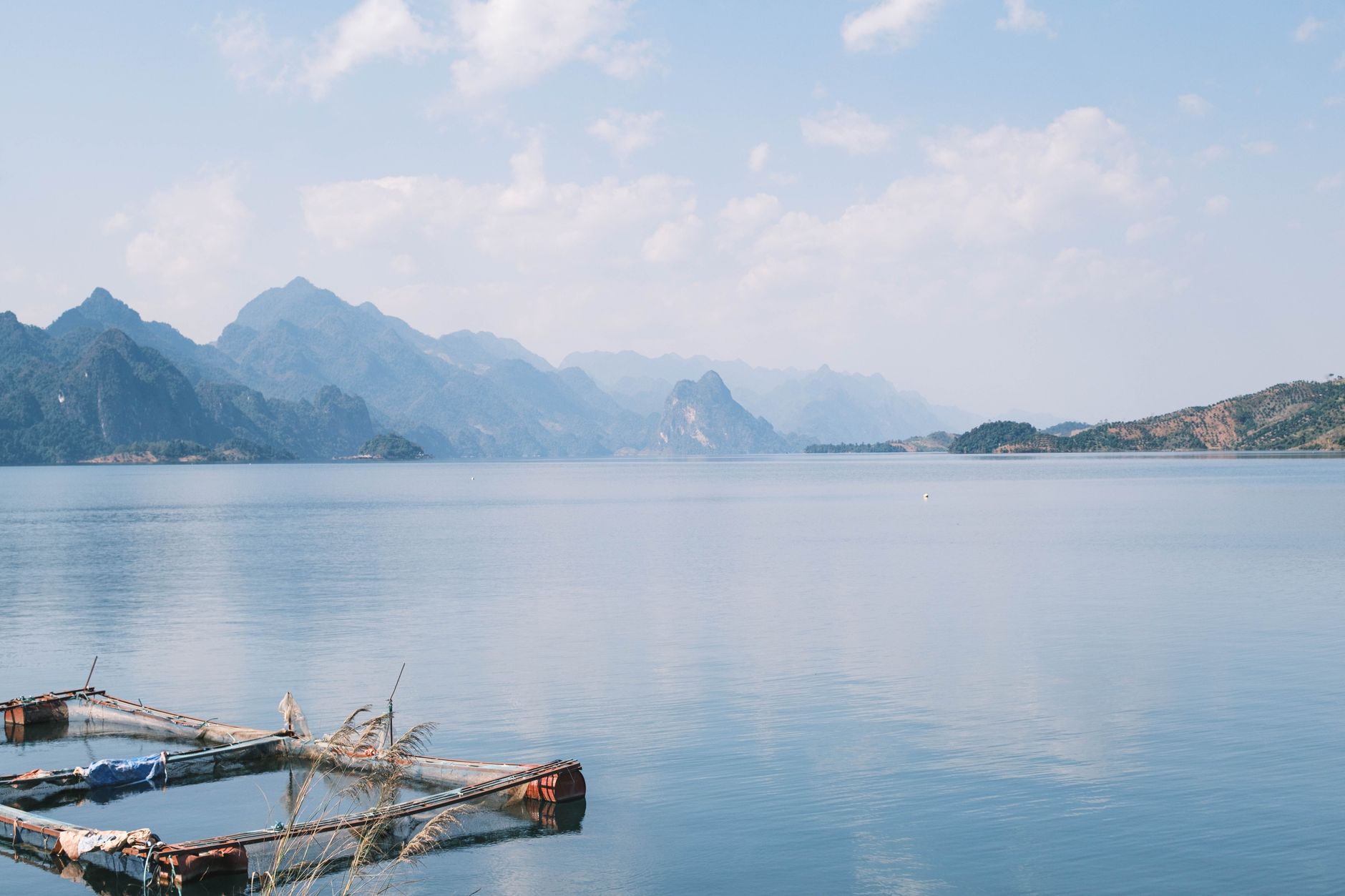 A serene mountain lake with clear blue sky and distant peaks reflecting in the calm water.