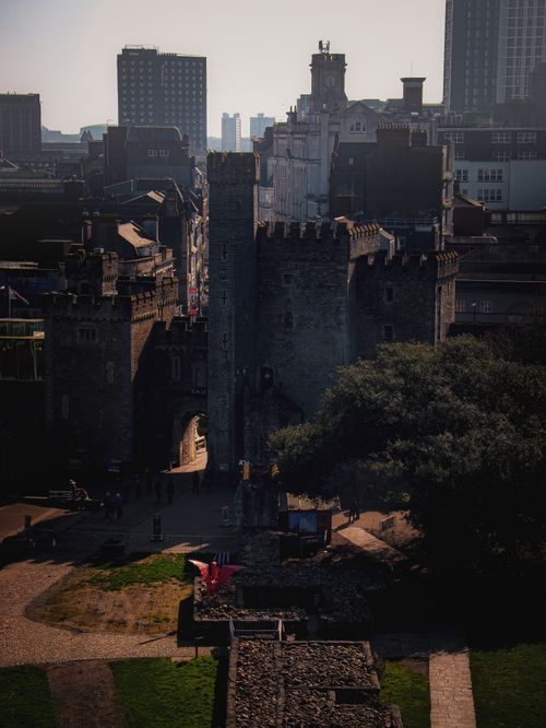 Free A historic medieval castle tower set against a modern urban skyline, captured in a dramatic light. Stock Photo