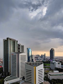 Urban skyline with modern skyscrapers under dramatic cloudy sky, showcasing architectural marvel.