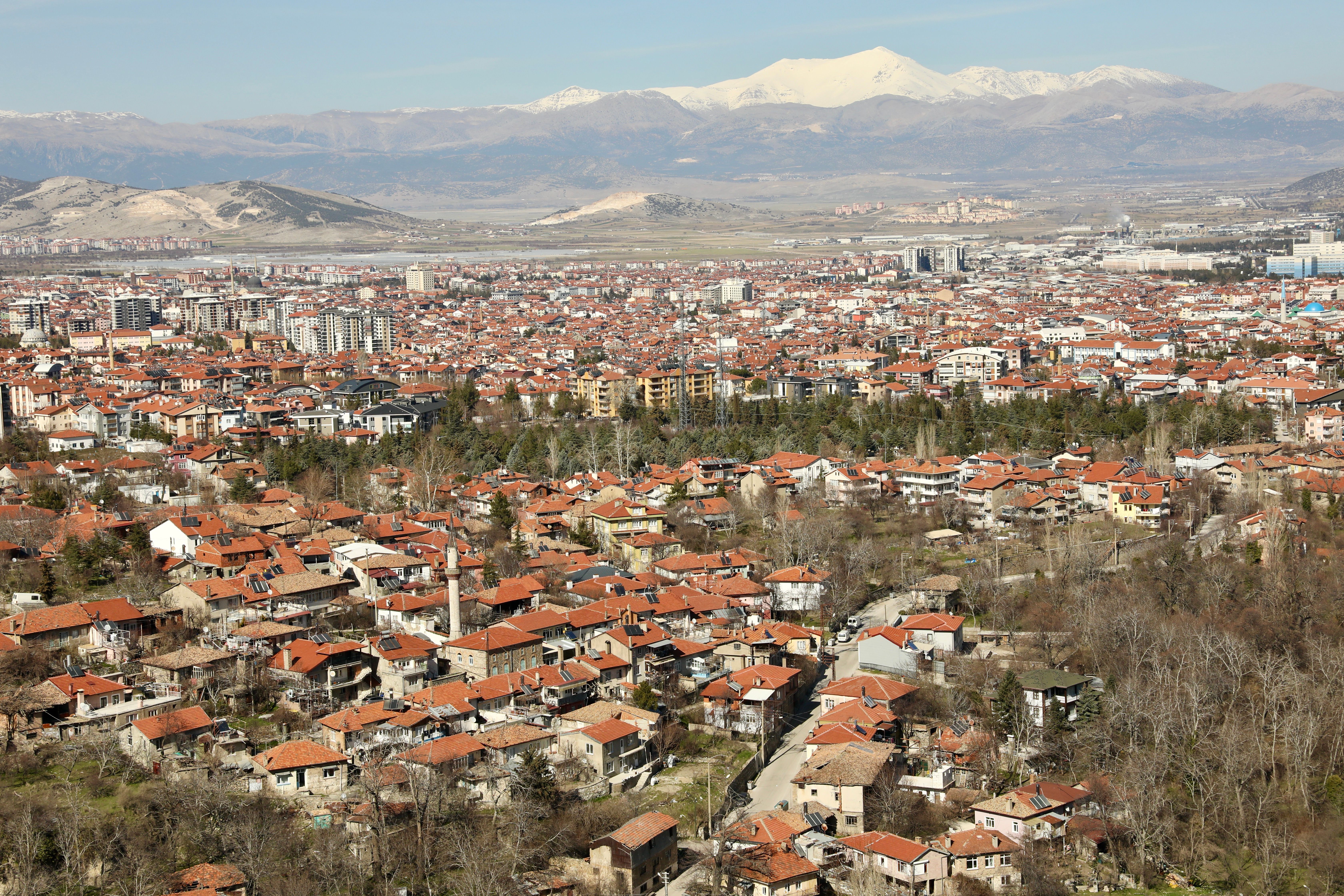 Aerial view of Isparta cityscape with red-roofed houses and distant mountains in Türkiye.