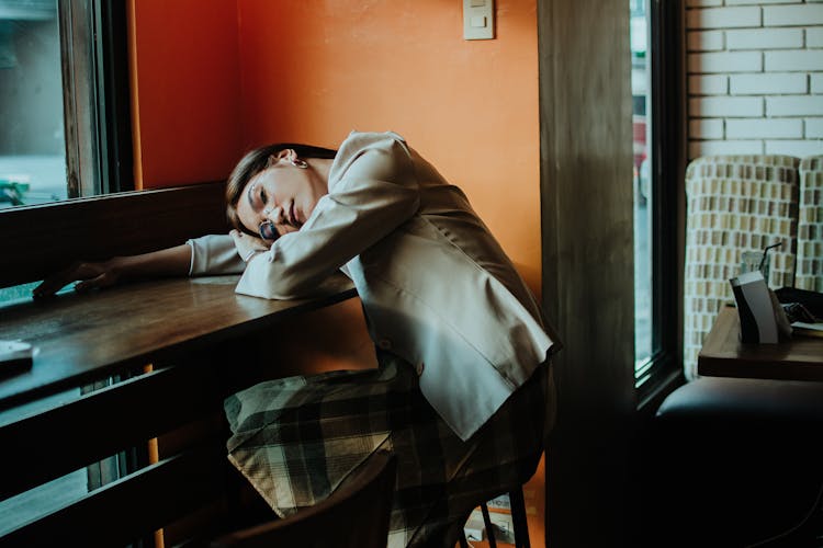 A Woman Napping On The Wooden Table