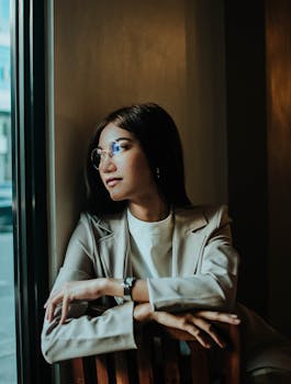 一位穿着西装的自信女性凝视着窗外，散发着专业与优雅