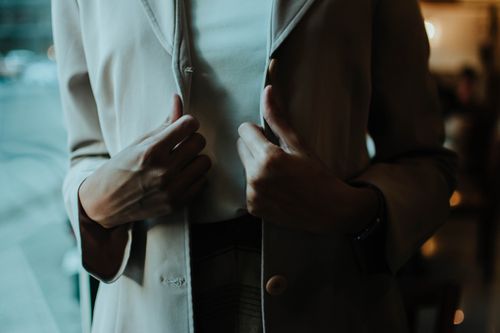 Free Close-up of a woman adjusting her blazer, showcasing elegance and style indoors. Stock Photo