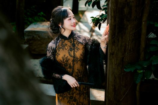 Woman in ornate dress enjoys a serene moment in a lush outdoor setting.