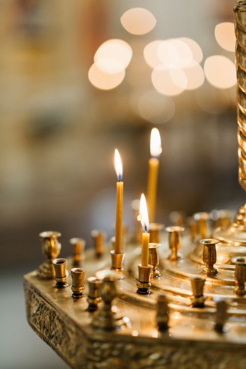 Free Close-up of a golden candlestick with lit taper candles in a dimly lit setting. Stock Photo