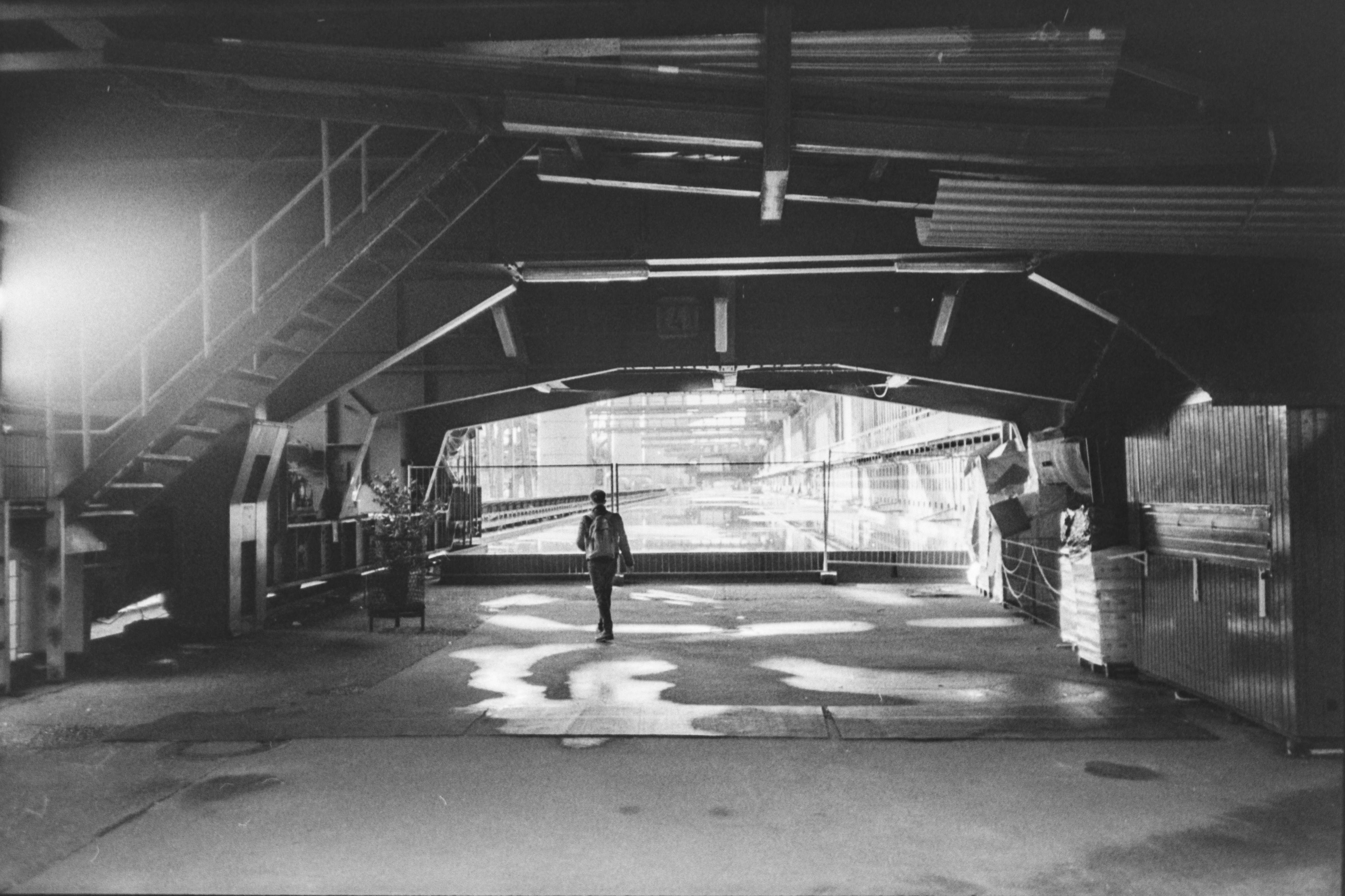 De franc Imatge en blanc i negre i malhumorada d'una persona sola caminant en un entorn industrial. Foto d'estoc