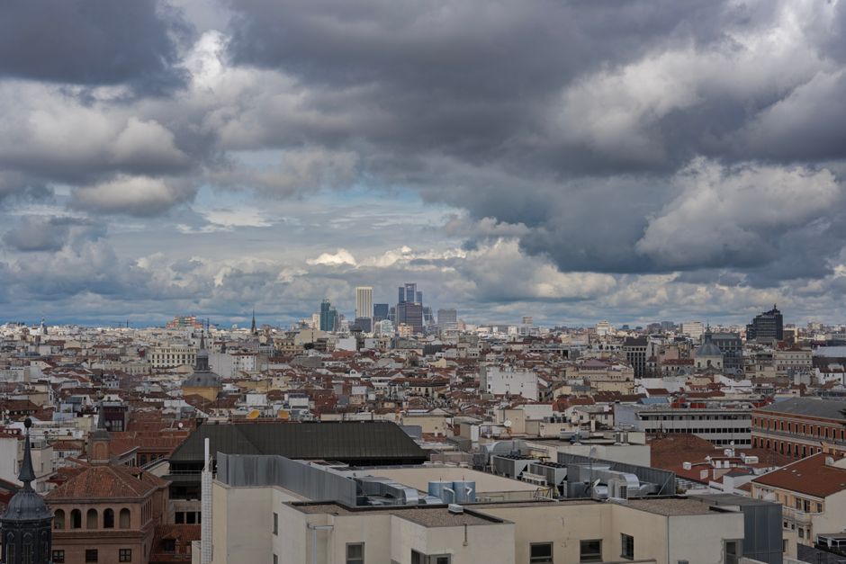 Vista aérea del skyline de Madrid con nubes dramáticas, mostrando rascacielos icónicos y edificios históricos.