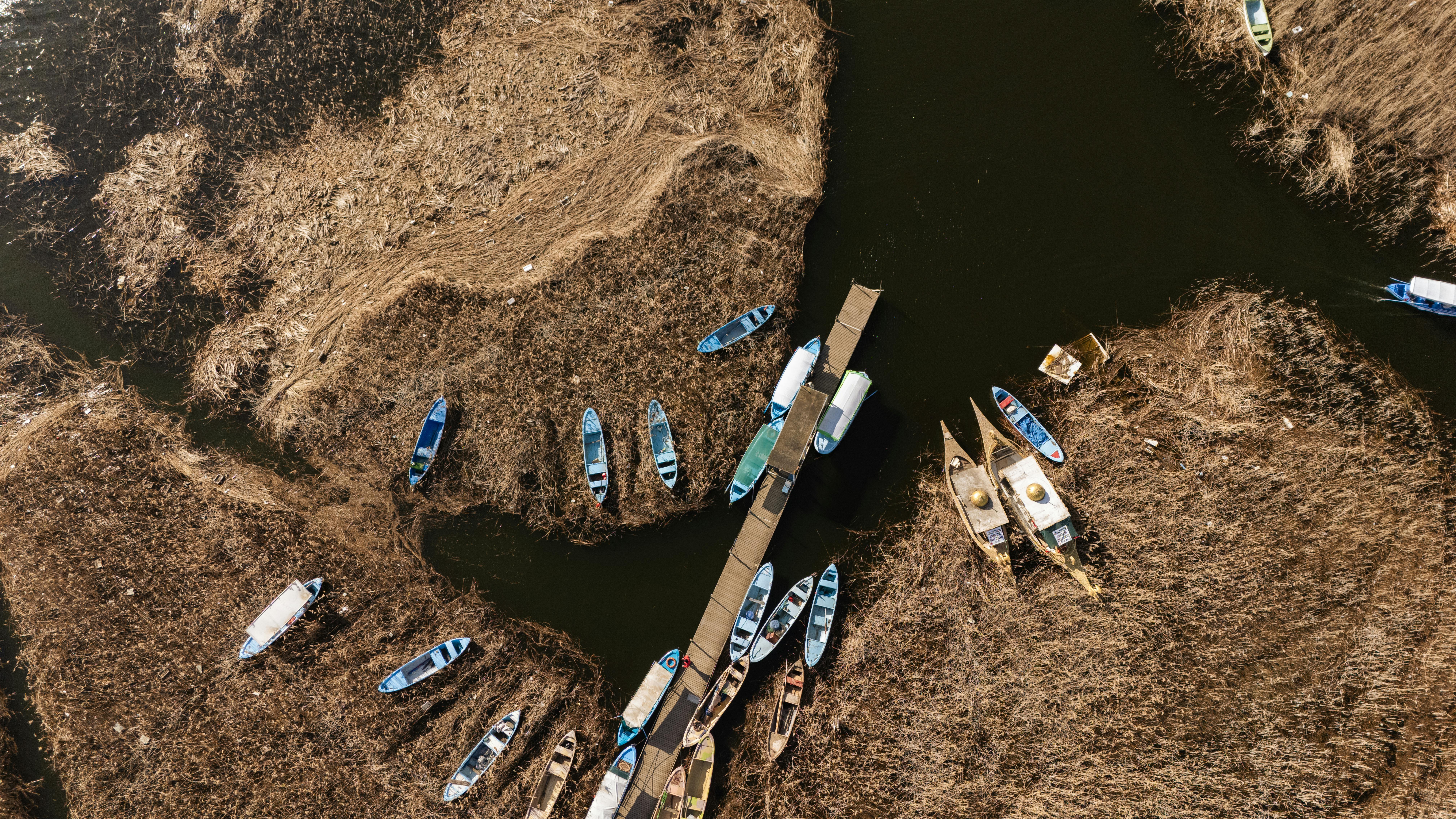 ingyenes Légifelvétel színes hajókról, amelyek nádassal körülvett török ​​vizes élőhelyeken horgonyoznak. Stockfotó