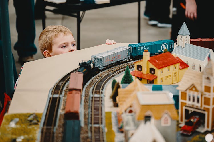 Boy Standing Beside A Train Toy