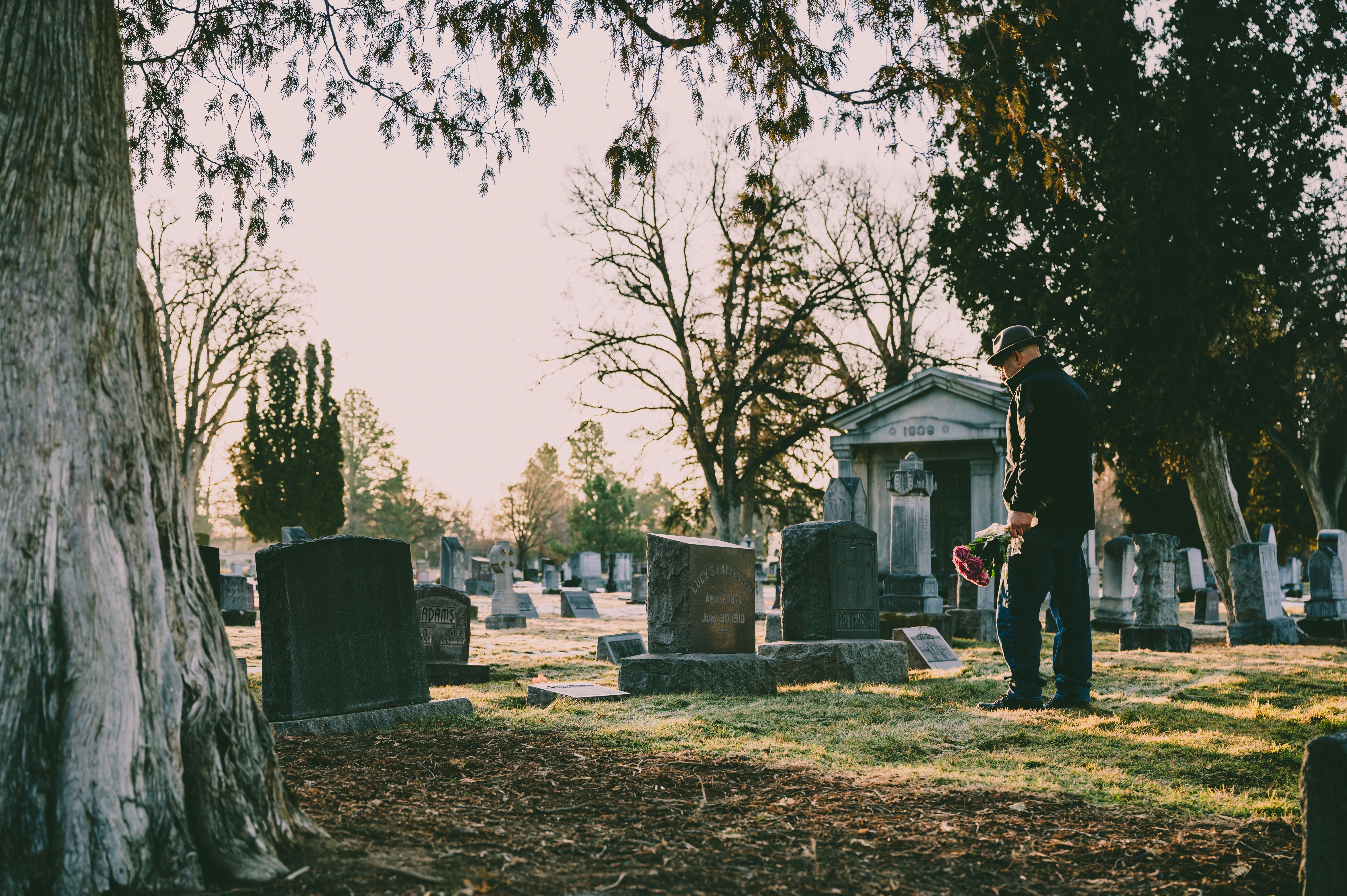 man in black jacket standing in front of grave