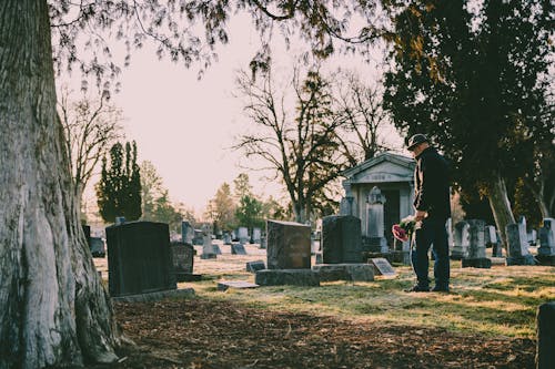 Free Man in Black Jacket Standing in Front of Grave Stock Photo