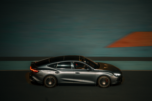 Dynamic panning shot of a sleek car driving through the streets of Kuwait City at night.