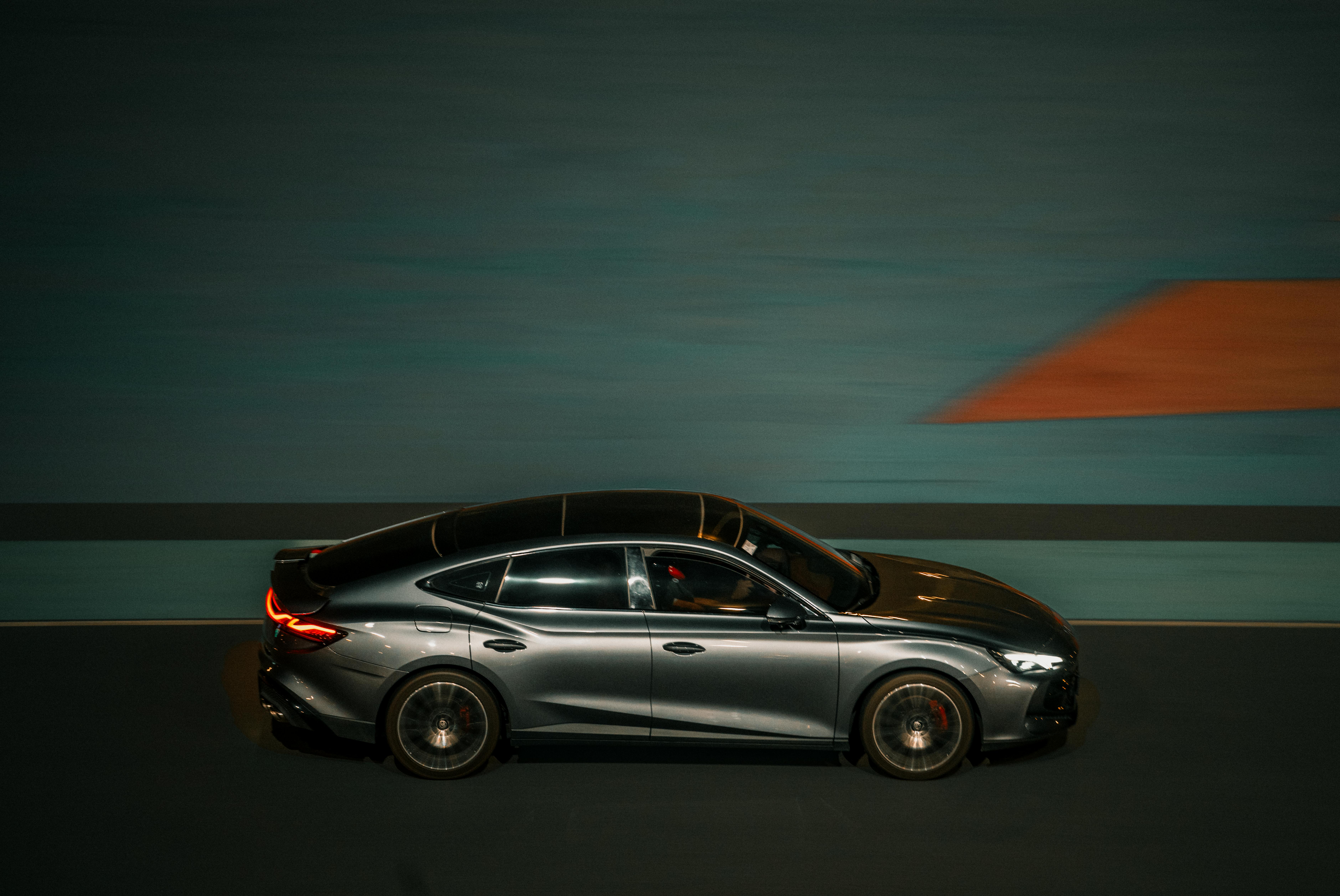 Free Dynamic panning shot of a sleek car driving through the streets of Kuwait City at night. Stock Photo