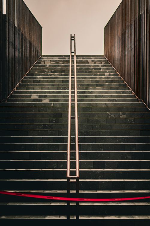 Free Dramatic urban staircase leading upwards, accented by a striking red tape, creating a modern architectural focus point. Stock Photo