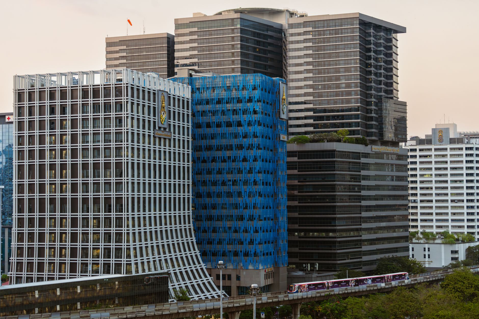 Sukhumvit skyline with BTS Skytrain running past condo towers at dusk
