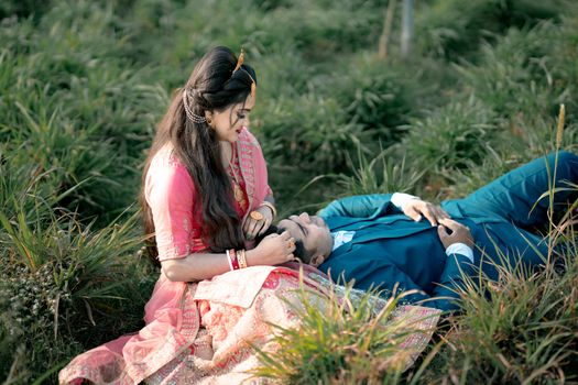 A loving couple in traditional attire sharing a moment on a grassy field, symbolizing romance and tradition.