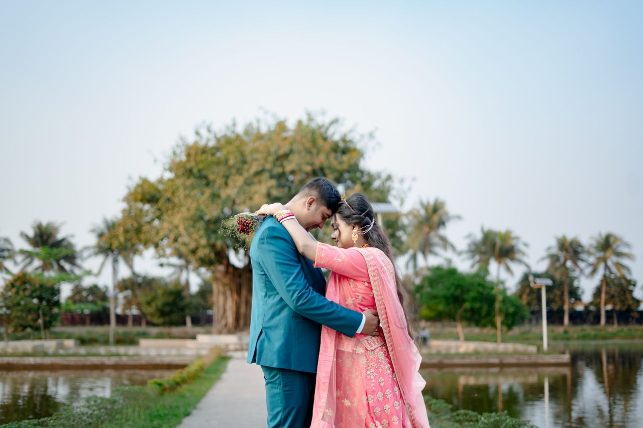 a couple in traditional attire embraces lovingly beside a tranquil pon
