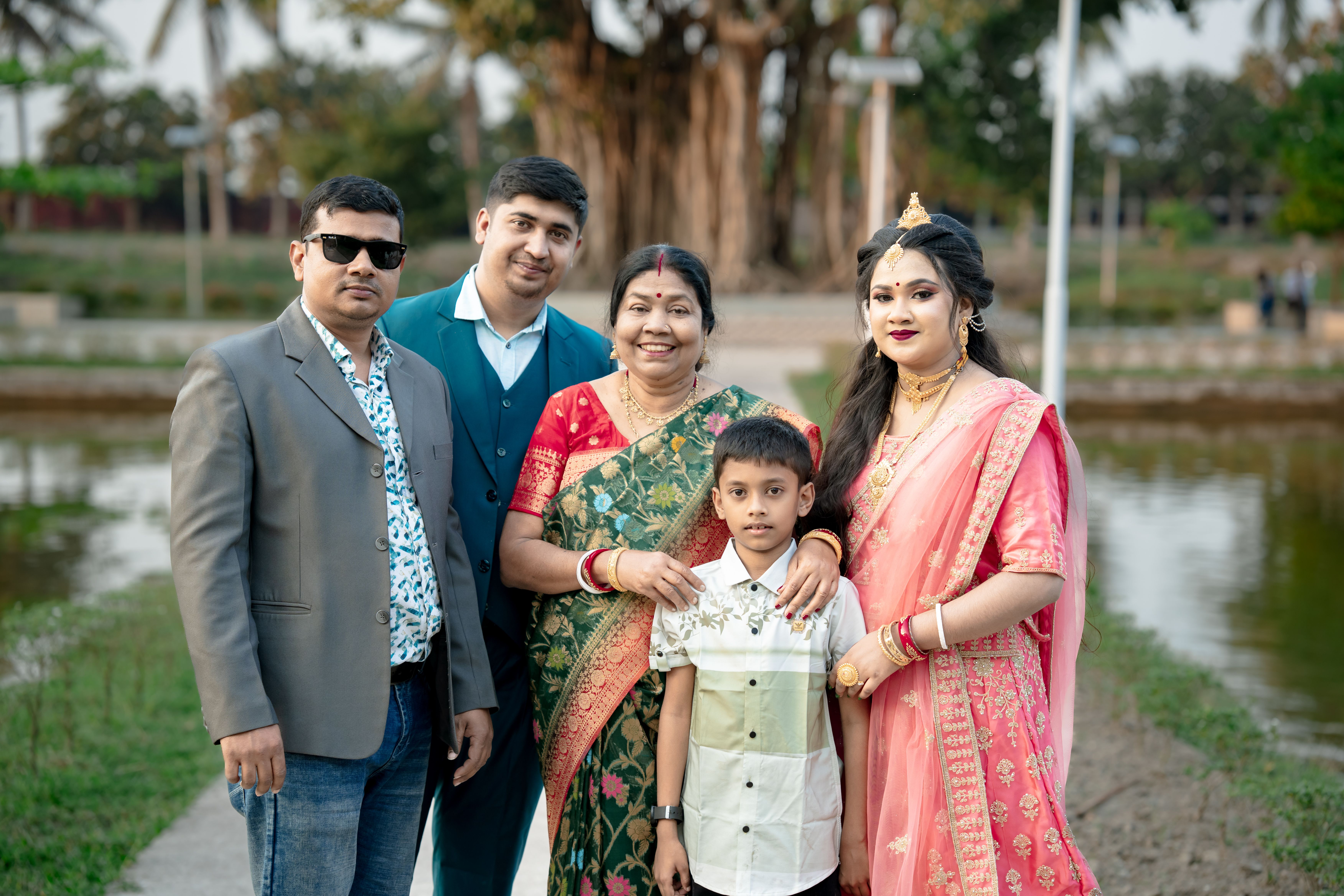 Gratis Una famiglia di cinque persone in abiti tradizionali indiani posa vicino a un tranquillo luogo all'aperto. Foto a disposizione