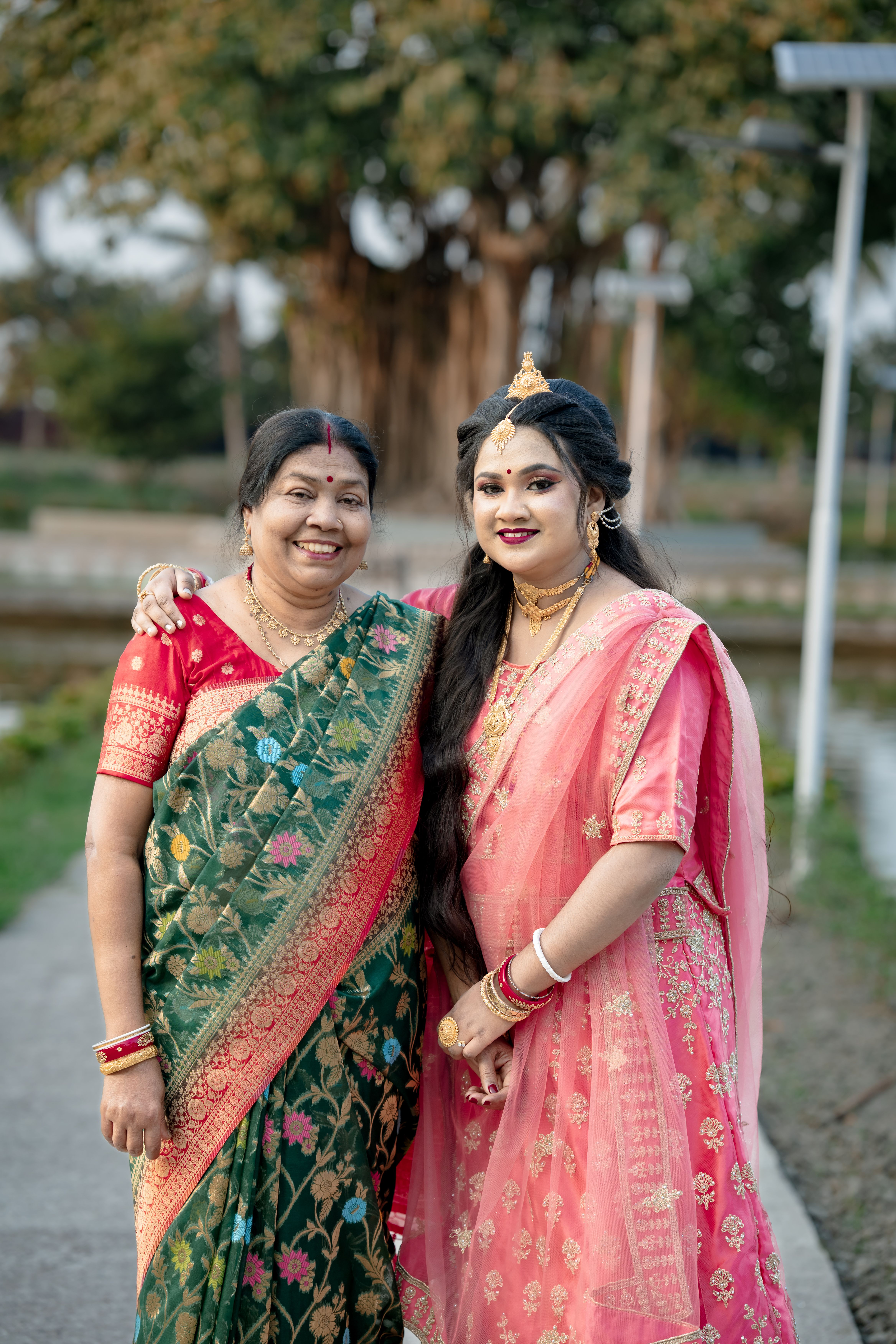 Gratis Madre e figlia sorridenti che indossano colorati sari tradizionali indiani all'aperto. Foto a disposizione