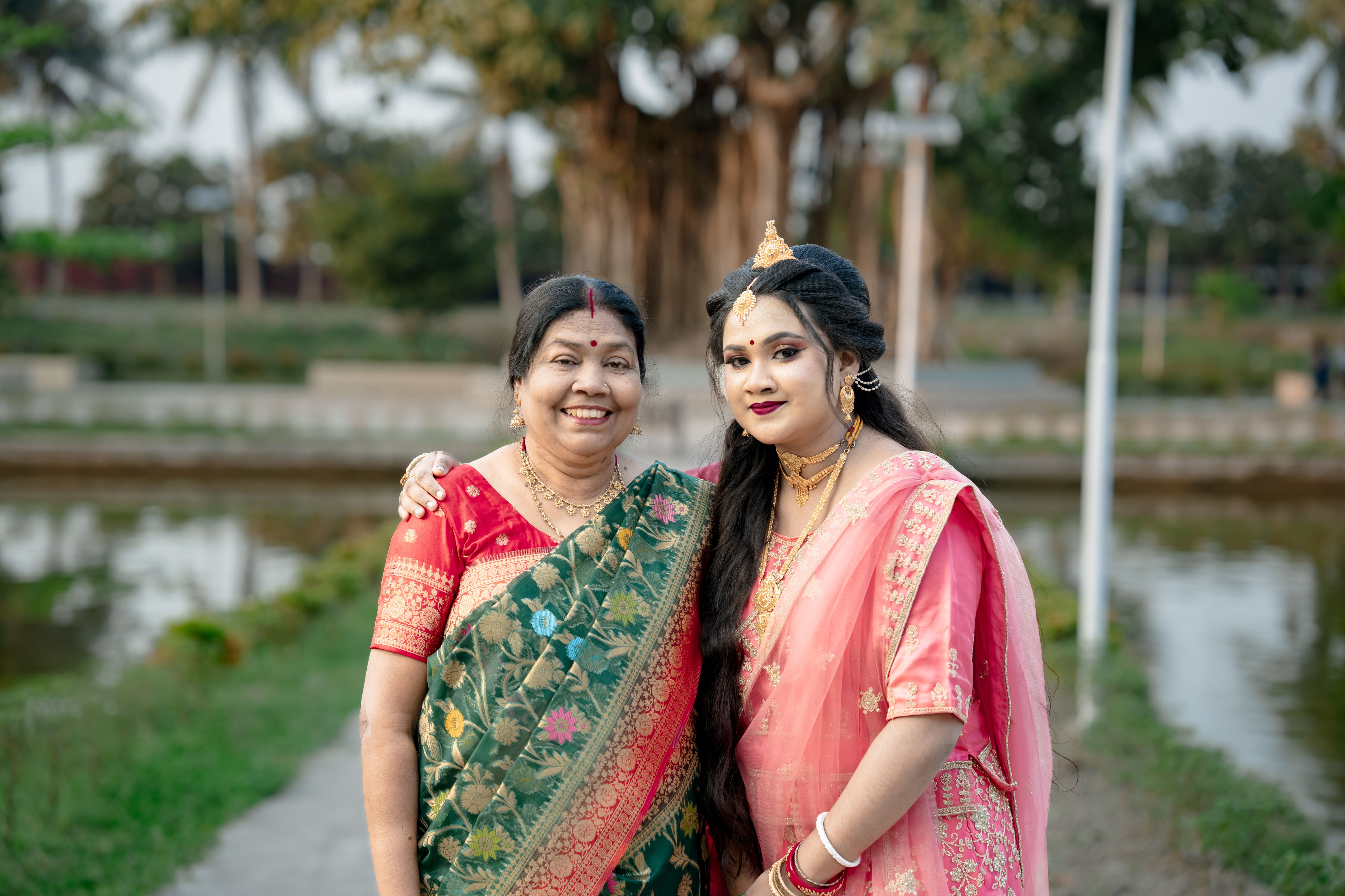 Gratis Una madre e una figlia gioiose che indossano abiti tradizionali indiani in un ambiente all'aperto. Foto a disposizione