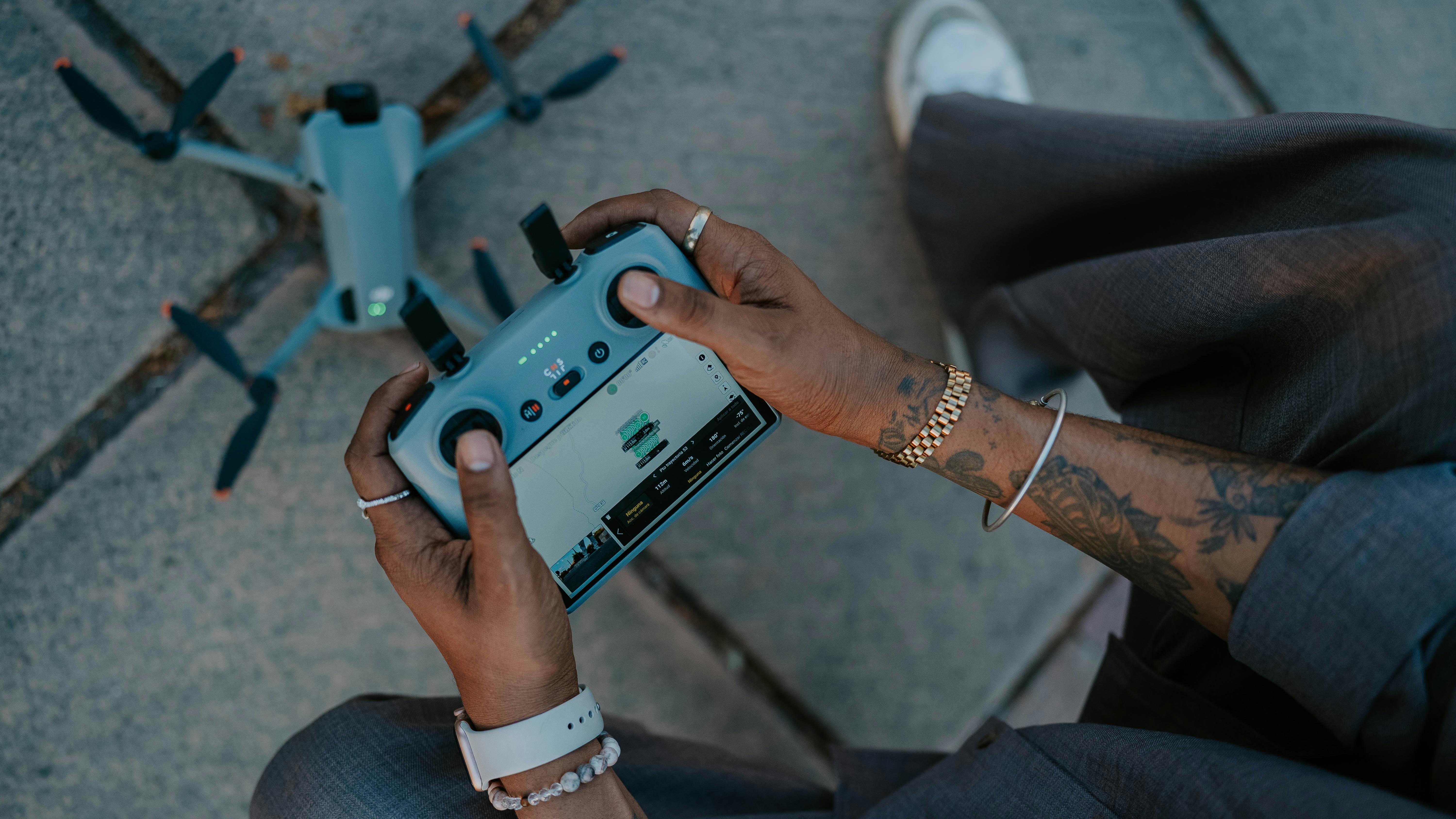 Gratis Mani tatuate che manovrano un drone, a sottolineare la tecnologia dei droni da esterno. Foto a disposizione