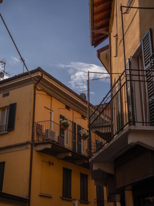 Free Rustic Italian buildings with balconies under a vibrant summer sky. Stock Photo