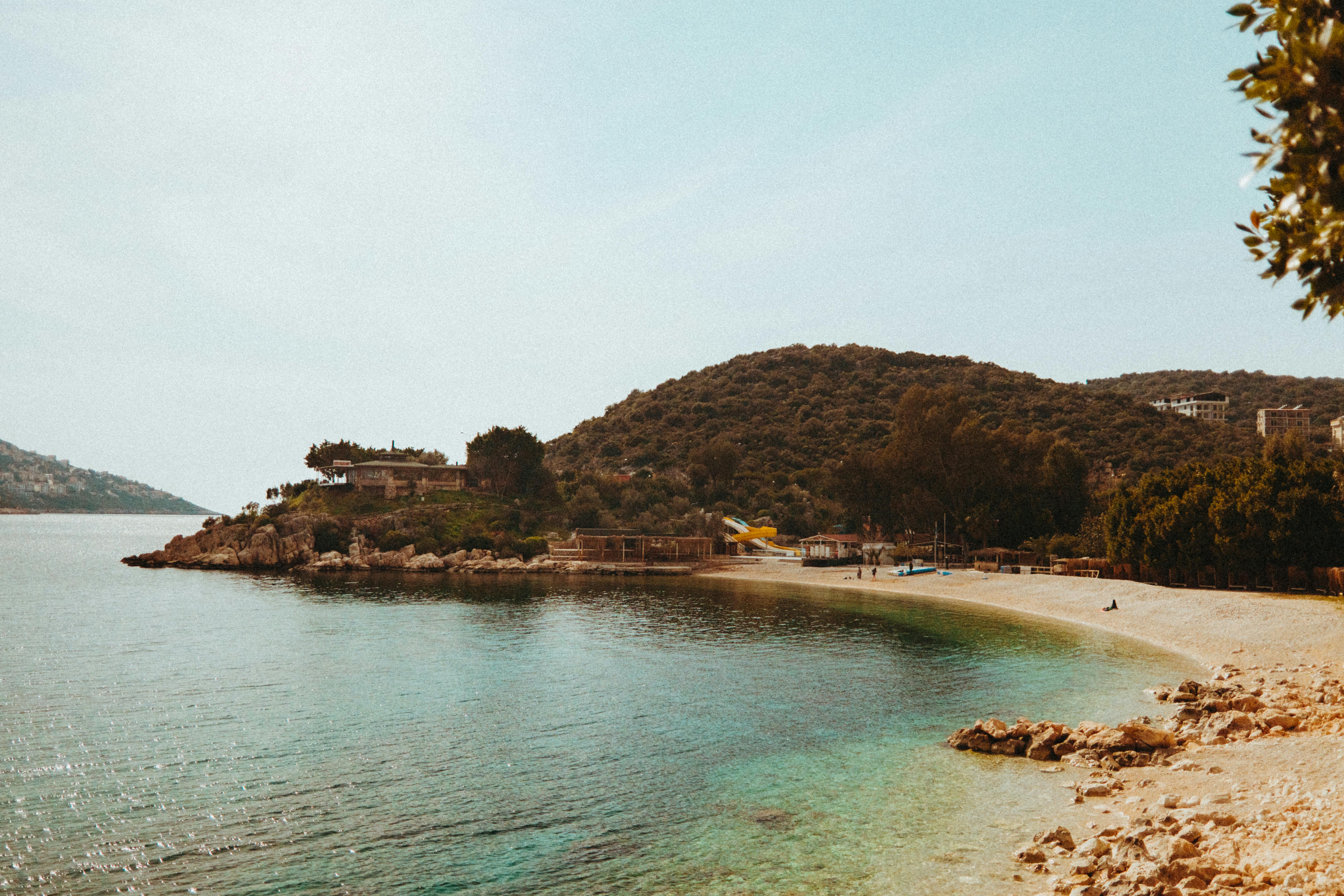 Relaxing beach scene with clear waters and lush greenery under a sunny sky, perfect for travel inspiration.