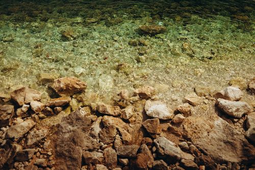 Free Stunning view of a rocky shoreline with crystal clear water revealing underwater stones. Stock Photo
