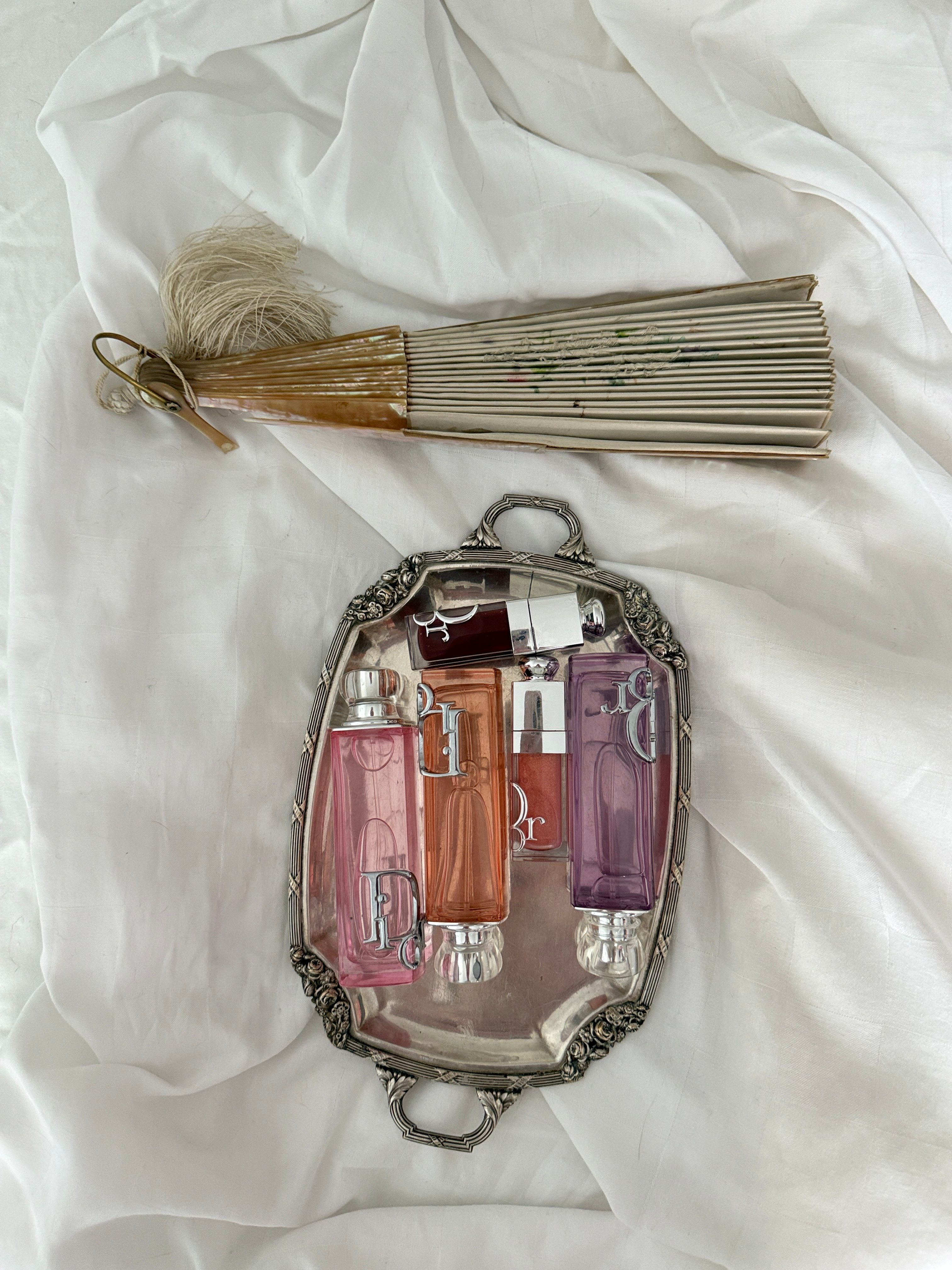 Stylish arrangement of vintage perfume bottles on a tray with a decorative fan.