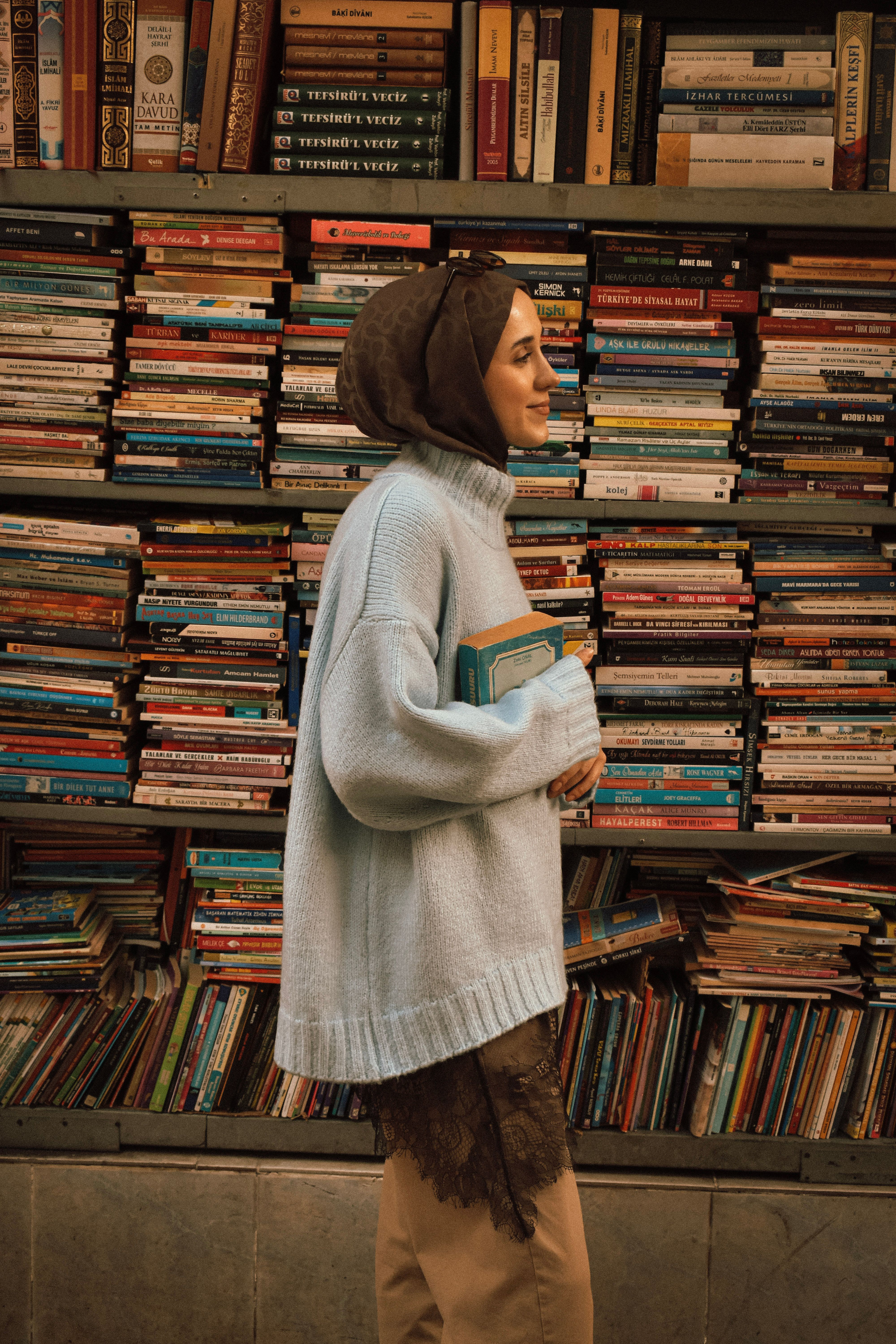 A woman in a cozy sweater holding books in a Bursa bookstore, Turkey.